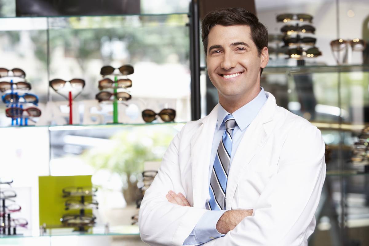 Smiling optician in front of glasses displays