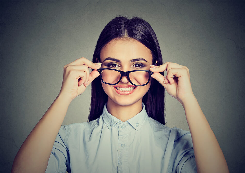 Smiling young woman taking glasses off