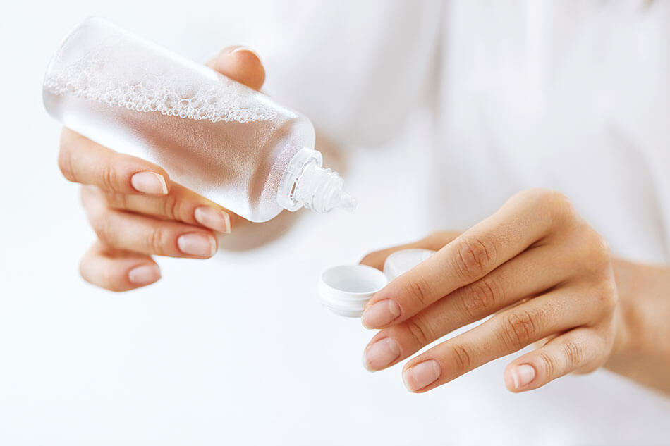 woman putting cleaning solution into contact lense case