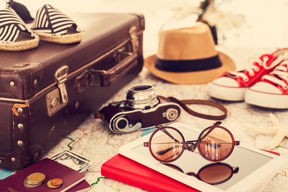 suitcase with camera, sunglasses, money, shoes, and items needed for traveling with contact lenses