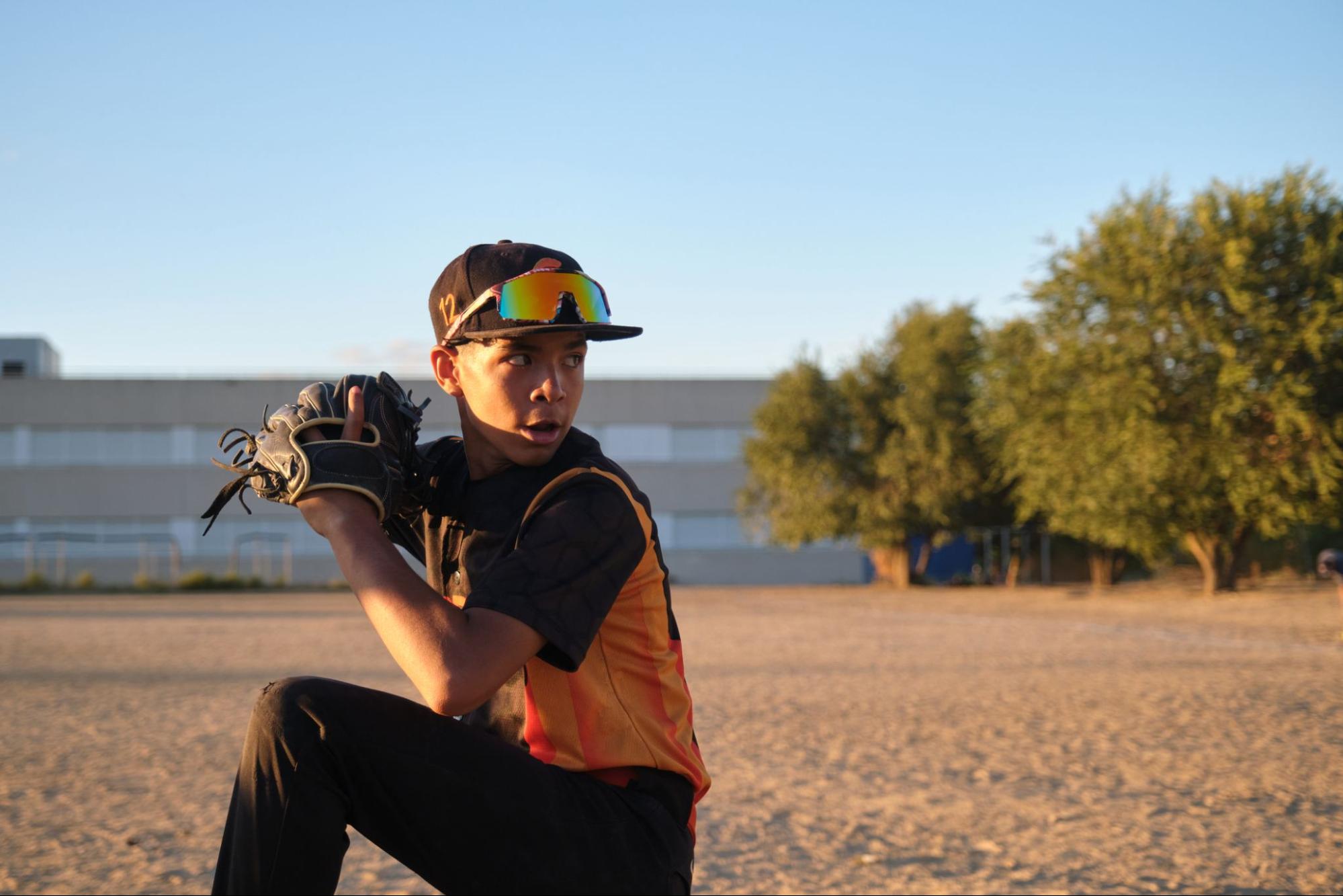Teen boy on a baseball diamond wearing sports eyewear pushed up on his cap