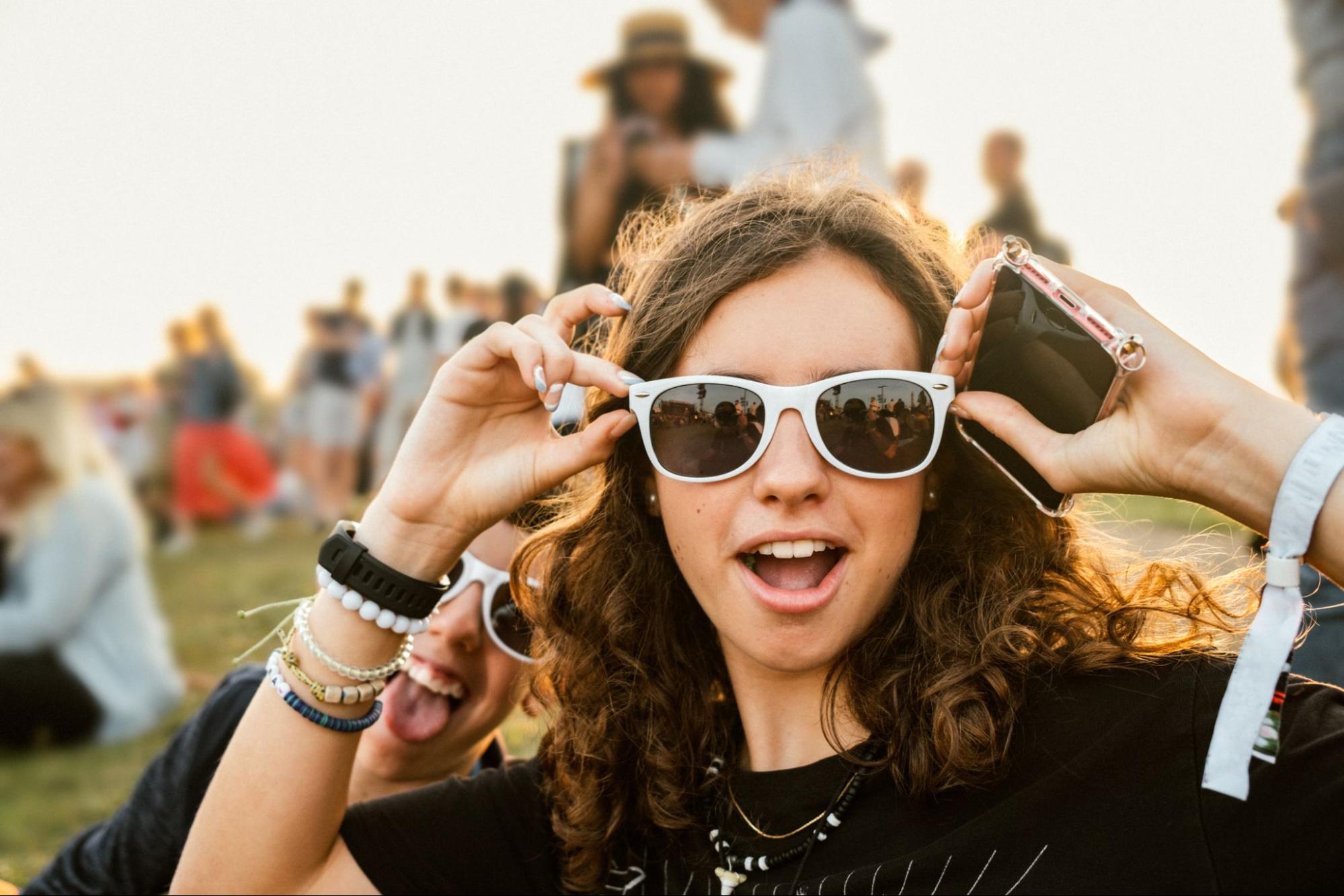 Teenage girl adjusting white sunglasses at an outdoor festival