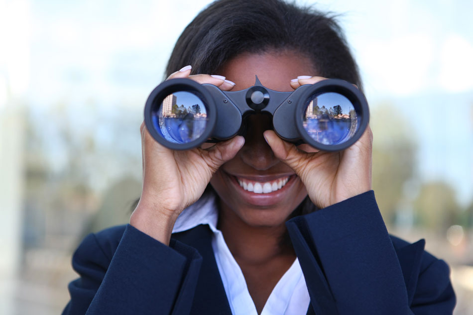 woman in business suit looking through binoculars