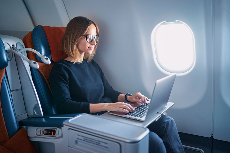 Woman wearing glasses on flight using laptop