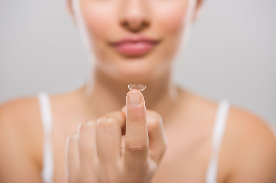 woman holding contact lens on her fingertip