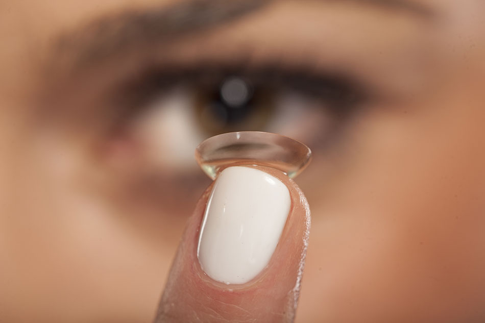 woman holding up weekly contacts on fingertip