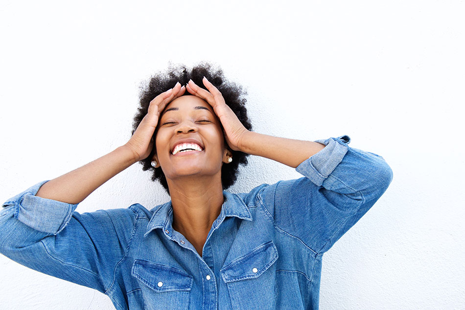 woman in jean jacket smiling and pulling hair back