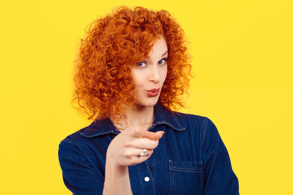 woman in jean shirt pointing, yellow background