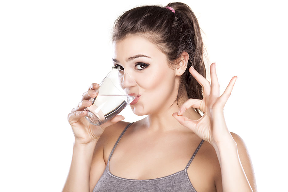 woman doing ok sign with hand while drinking cup of water