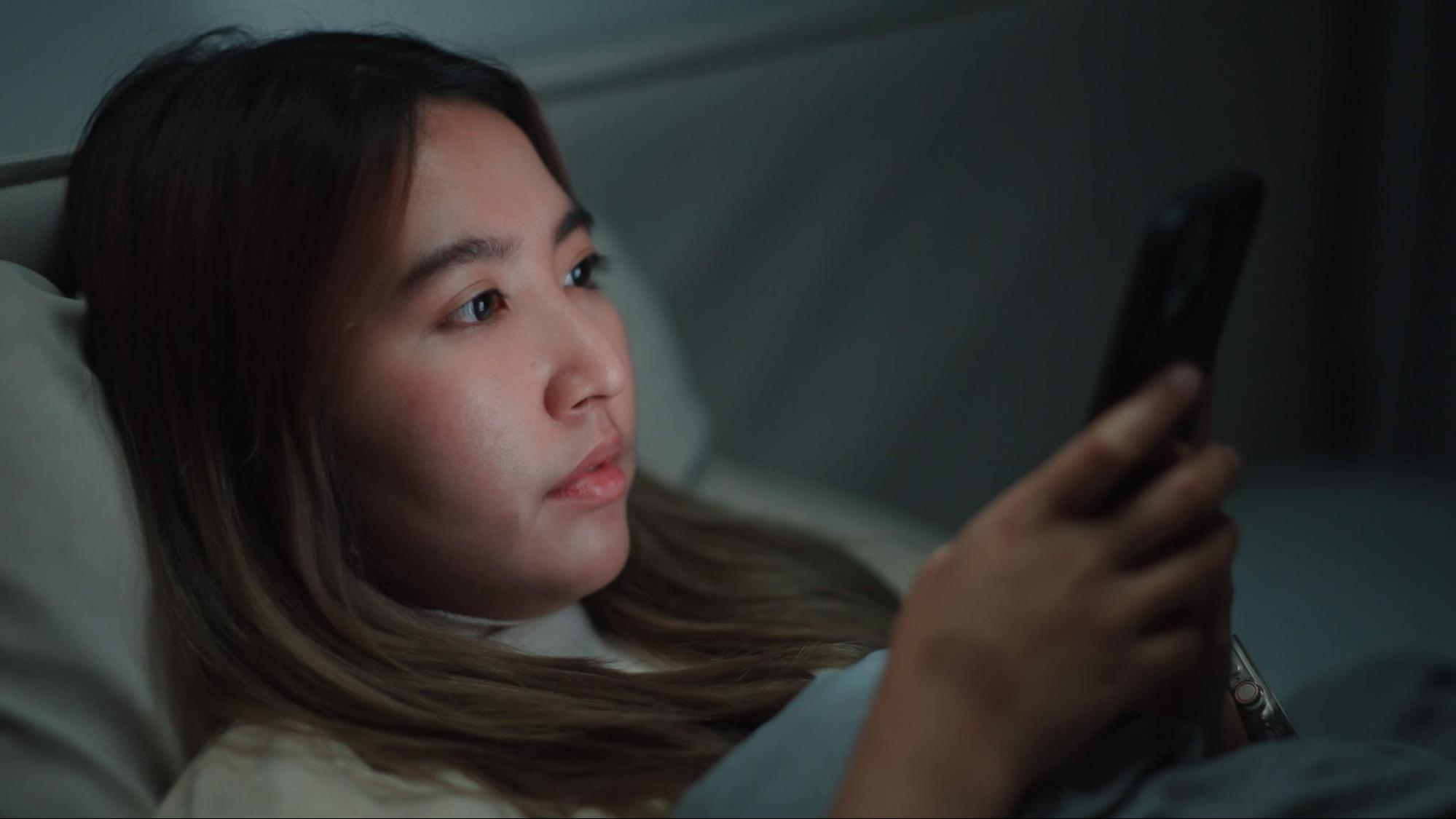woman using smartphone in bed at night