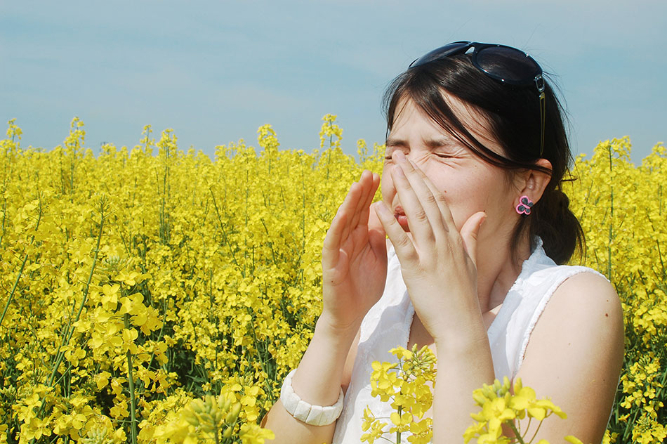 Woman surrounded by yellow flowers and sneezing