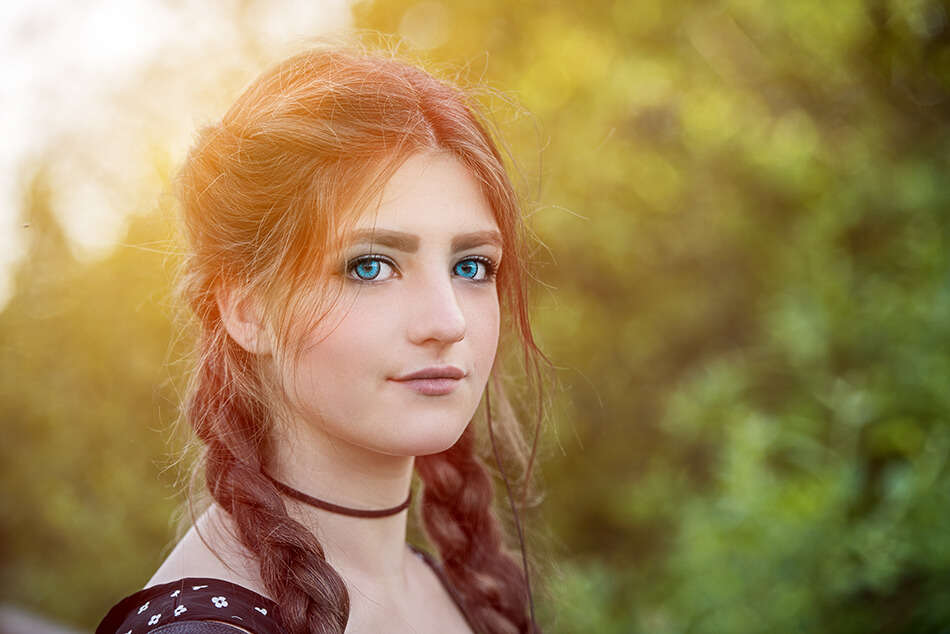 young-woman with auburn hair in braids wearing vivid blue colored contact lenses