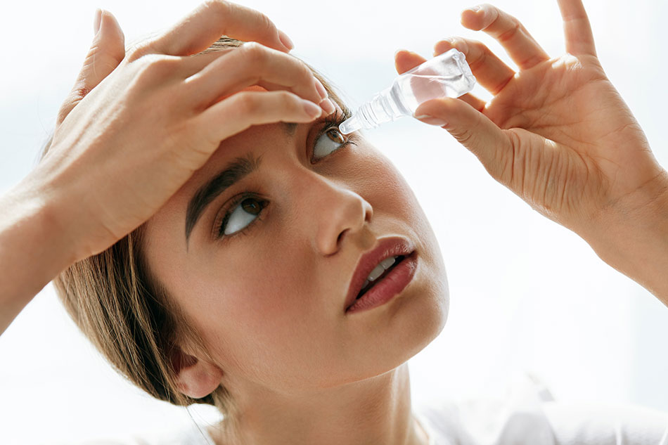 Young woman putting eye drops in